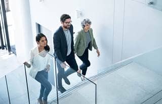 Business professionals walking up the stairs in a modern, clean office space.