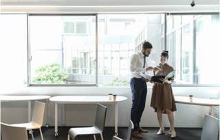 Two financial professionals in a modern office discussing how to mitigate risk.