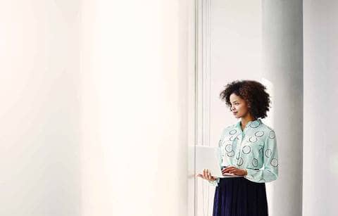 Business professional holding a laptop while standing.