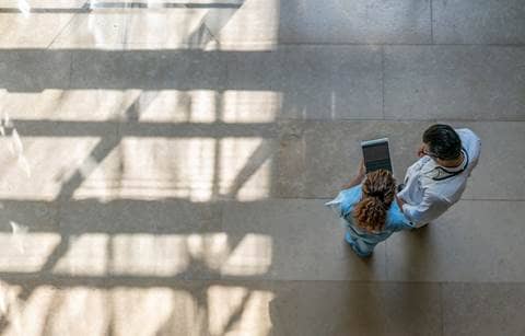 Two medical professionals review information on a tablet.