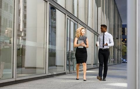 Two employee benefit professionals talking outside of an office.