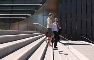 Two business owners walking down a column of stairs together.