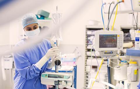 Doctor in an ER room monitoring a piece of equipment.