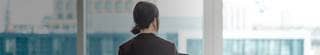 Young businesswoman with digital tablet, standing against office window with city view in modern commercial building.